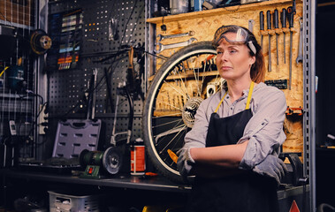 Obraz na płótnie Canvas Old woman with eyewear dressed in work wear in workshop