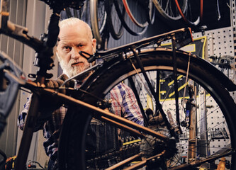 Professional bicycle repairman working in modern repair shop