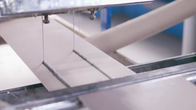 cardboard products. a cardboard factory produces paper corners. production. cardboard. paper. applying glue to cardboard. adhesive composition