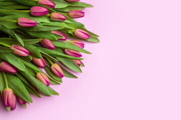 Bouquet of purple tulips on a pink background. Flat lay, top view.