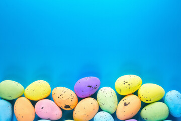 colorful multicolored eggs on a blue background at the bottom.