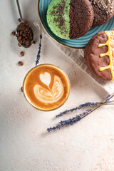 A glass of cappuccino or latte with foam and an artistic pattern. Coffee and cookies on the table for breakfast, top view and copy space