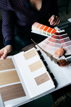 Designer's Hand Choosing Color From Various Color Swatches In Office