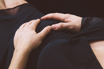 Herz am Babybauch - Mann und Frau mit Hand an Babybauch