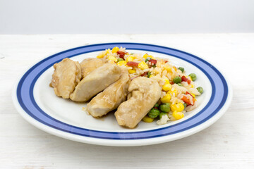 Chicken chops with rice and vegetables on a wooden table
