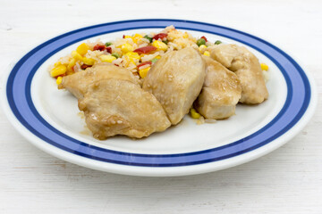 Chicken chops with rice and vegetables on a wooden table