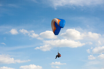 Alone paraglider flying in the blue sky against the background of clouds. Paragliding in the sky on...