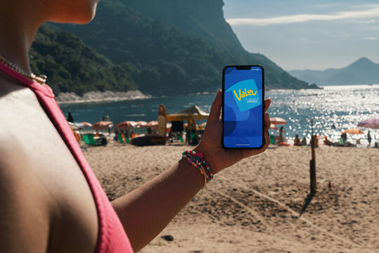 Girl on the beach holding a smartphone with Valeu delivery app on the screen. Rio de Janeiro, RJ, Brazil. March 2022