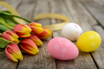 Fototapeta na wymiar Colorful Easter eggs and tulips on wooden background
