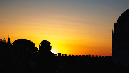 silhouette of a boy with headphones listening to music at sunset