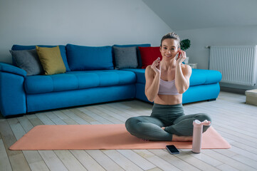 Obraz premium Woman using airpods and a smartphone while training at home