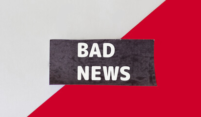 Bad news,text on black sticky note and red and white background.