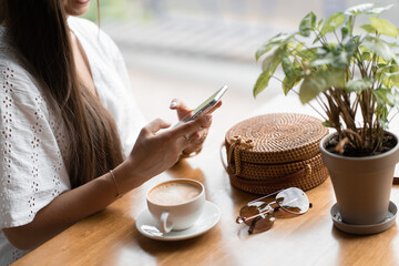 girl with long hair sits at a table in a cafe and sends text messages
