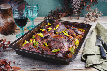 Traditional barbecue haunch of hare with leek in red wine sauce served as close-up in a rustic tray