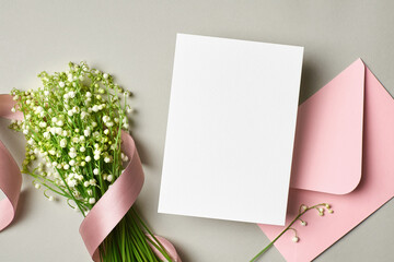 Invitation or greeting card mockup with envelope and lily of the valley flowers