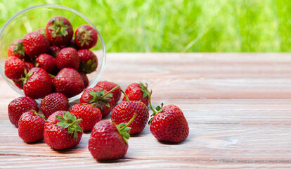 Ripe and tasty strawberry in bowl on a wooden background. Copy space. Close-up.
