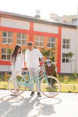 loving couple walks around the city with a bicycle and a basket of flowers
