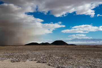 Dust storm in desolate, barren desert landscape showing the environmental damage from lithium mine...