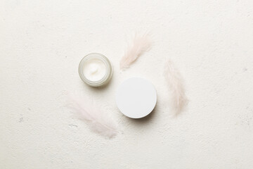 Spa cosmetic product, cream jar, branding mock up, top view with feathers background. Flat lay