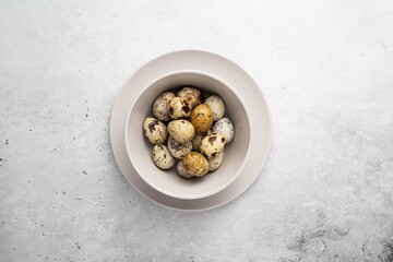 Fresh, farm, raw quail eggs in plate on light background. Protein diet. Healthy diet. Top view,...