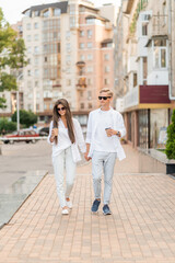 guy with a girl in white clothes walks around the city and drinks coffee