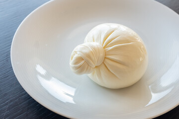 Buratta cheese on a white plate. Side view from above