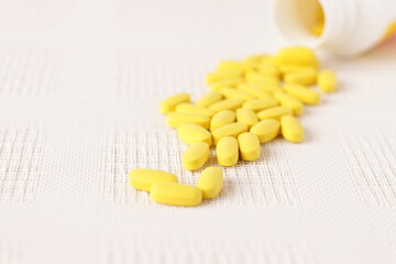 Fototapeta na wymiar Yellow pills vitamins, bunch of tablets on white table