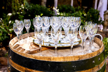 Empty wine glasses arranged on a wooden barrel outdoors