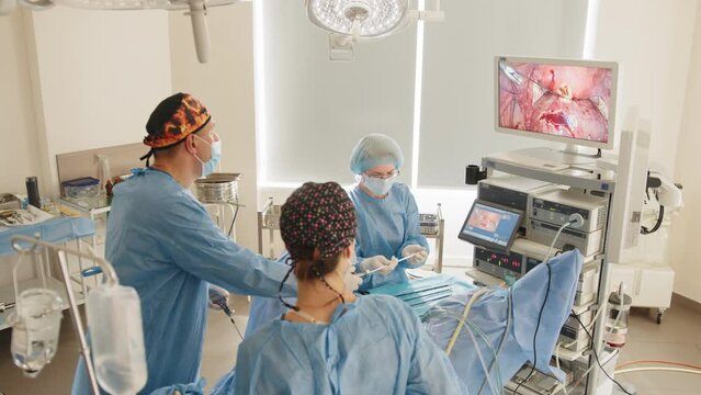 View from above surgeons team preforming operation in hospital operating theater, male surgeon operating patient in operating room,,working with surgical laparoscopy instruments. Gynecology
