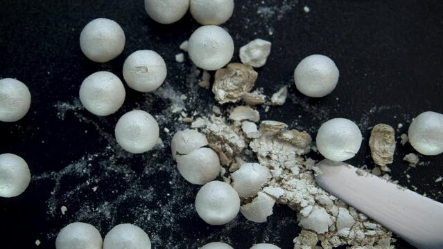 Mother-of-pearl powder in balls on a black background close-up.Cosmetic product texture. Decorative cosmetics for the face.