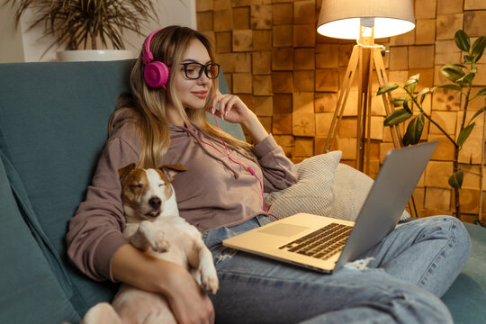 A girl with a dog watching a movie on a laptop with headphones. Pets and pet friends for people