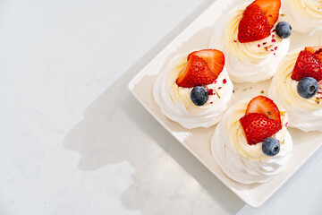 strawberries, blueberries and cream decorates to Anna Pavlova cakes.