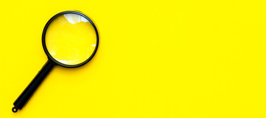 Black magnifier on a yellow  background.