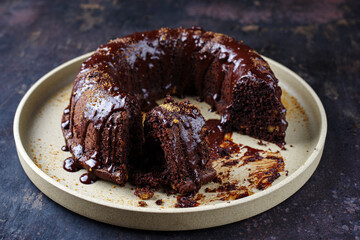 Traditional chocolate bundt cake with icing glaze topping and muscovado brown sugar served as close-up on a plate