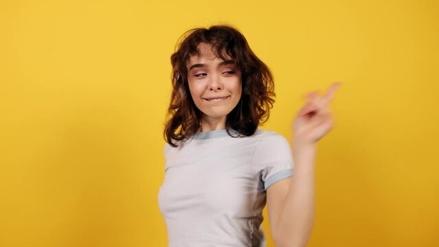Portrait of funny girl dancing and waving her hands rhythmically. Attractive young girl on yellow background. High quality 4k footage