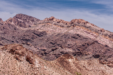 Nelson, Nevada, USA - May 21, 2011: Mountains along Eldorado canyon shows layers of rocks in different colors under blue cloudscape.