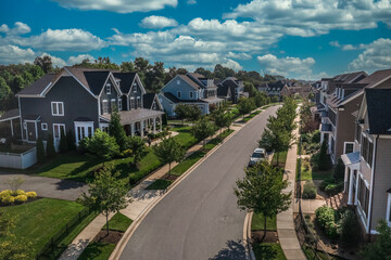 Aerial view of modern upper class suburban American real estate development community, large single family homes with vinyl and brick siding portico leading up to the entrance cloudy blue sky - obrazy, fototapety, plakaty