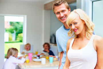Mature couple with their children having breakfast in background. Portrait of a happy mature couple with their children having breakfast in background.