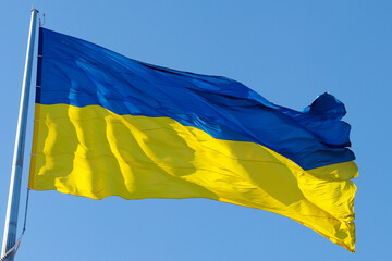 The national flag of Ukraine flutters in the wind against the blue sky close-up. Concept of freedom, independence and patriotism