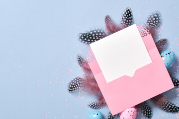A mock-up of a pink envelope with a blank sheet of paper on with Easter eggs and feathers.