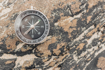 Closeup, analogical compass on a rock, concept orientation, summer travel.