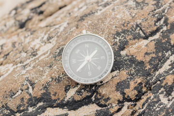 Closeup, analogical compass on a rock, concept orientation, summer travel.