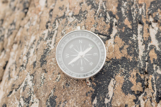 Closeup, analogical compass on a rock, concept orientation, summer travel.