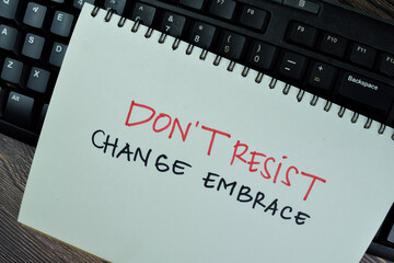 Dont't Resist Change Embrace write on a book isolated on Wooden Table.