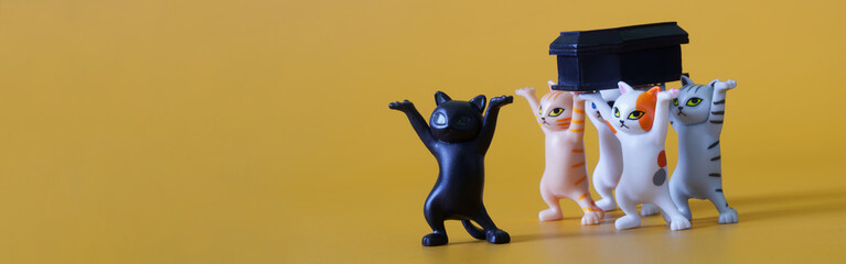 Five cute toy dancing kittens are carrying a black coffin. Funeral procession dancing with the...