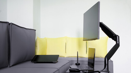 Thin monitor is mounted next to a loft sofa, on a table, using a gas-lifted metal swivel bracket....