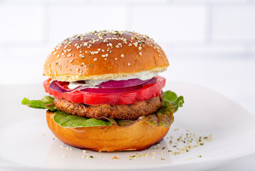 Healthy  veggie burger on a brioche bun with tomato, red onion and leafy greens; copy space