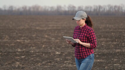 Farmer woman works with her digital tablet in field sown in spring. Smart farming technologies....
