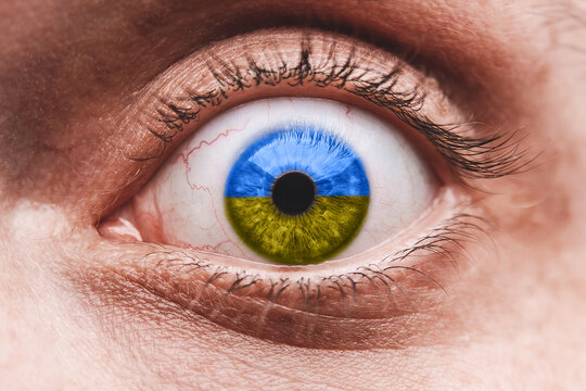 Concept against military action. The eye of a frightened man with a pupil in the colors of the flag of Ukraine.