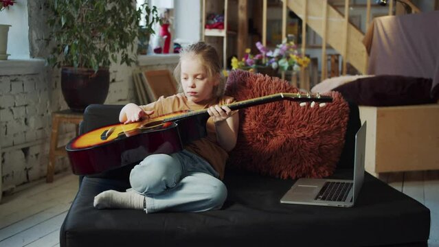 A girl learns to play the guitar on her own using the Internet